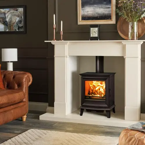 Black wood burning stove installed inside a cream fireplace surround in a traditional living room.